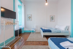 Quarto com cama, cadeira, televisão e um cabideiro.
