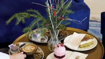A dining table with a coffee cup, a dessert, and a vase with branches and berries.