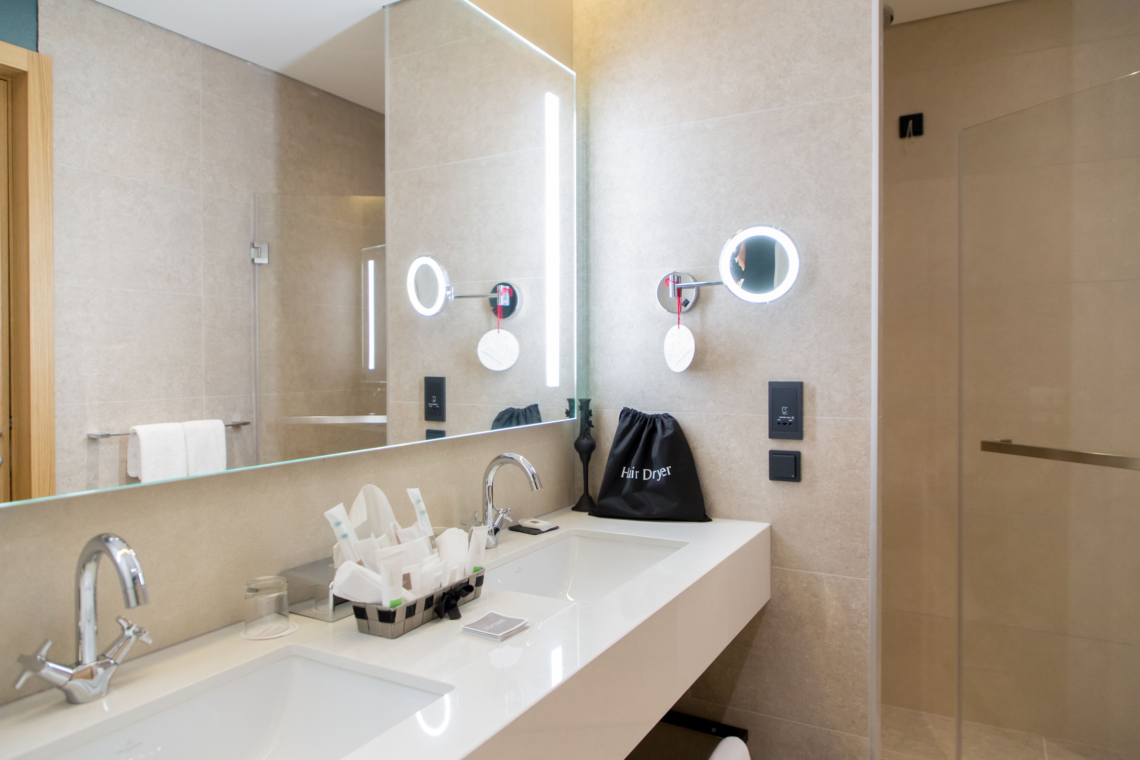 Un baño moderno con dos lavamanos, un espejo grande y una cabina de ducha de vidrio.