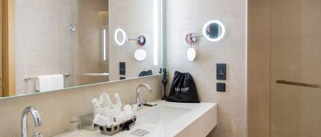 Un baño moderno con dos lavamanos, un espejo grande y una cabina de ducha de vidrio.