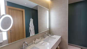 A modern bathroom with two sinks, a large mirror, and a robe rack.