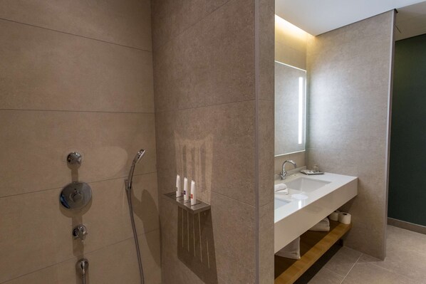 Une salle de bain moderne équipée d’une douche, d’un lavabo et d’un miroir.