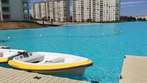 A swimming pool with a dock and inflatable boats, surrounded by high-rise buildings. - Departamento Algarrobo Condominio Laguna (Algarrobo)