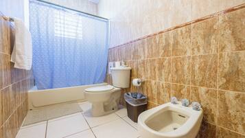 Un baño con inodoro, bidé y cortina de ducha.
