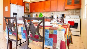 A kitchen with wooden cabinets, a refrigerator, a microwave, a stove, and a dining table with chairs. - Colinas del Atlantico Vacational House 2nd Floor (Isabela)