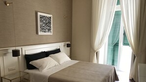 A neatly arranged bedroom with a bed, bedside tables, a hanging lamp, and a window with curtains. - NovaNova (Naples)