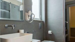 A modern bathroom with a large mirror, a sink, a toilet, and a shower area. - NovaNova (Naples)