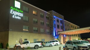 Un bâtiment de la chaîne Holiday Inn Express & Suites, avec une façade en briques, de nombreuses fenêtres et un parking où sont stationnés plusieurs véhicules.