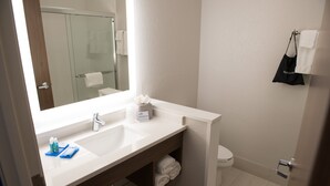 Une salle de bain moderne avec un grand miroir, deux lavabos, des toilettes et une douche à parois de verre.