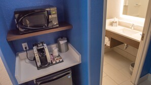Une petite cuisine équipée d’un four à micro-ondes, d’une machine à café et d’un petit réfrigérateur.