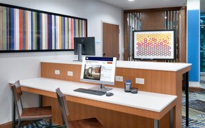 A reception desk with a computer, a framed picture, and a sign indicating a storage room. - Holiday Inn Express & Suites Gainesville I-75 by IHG (Gainesville)