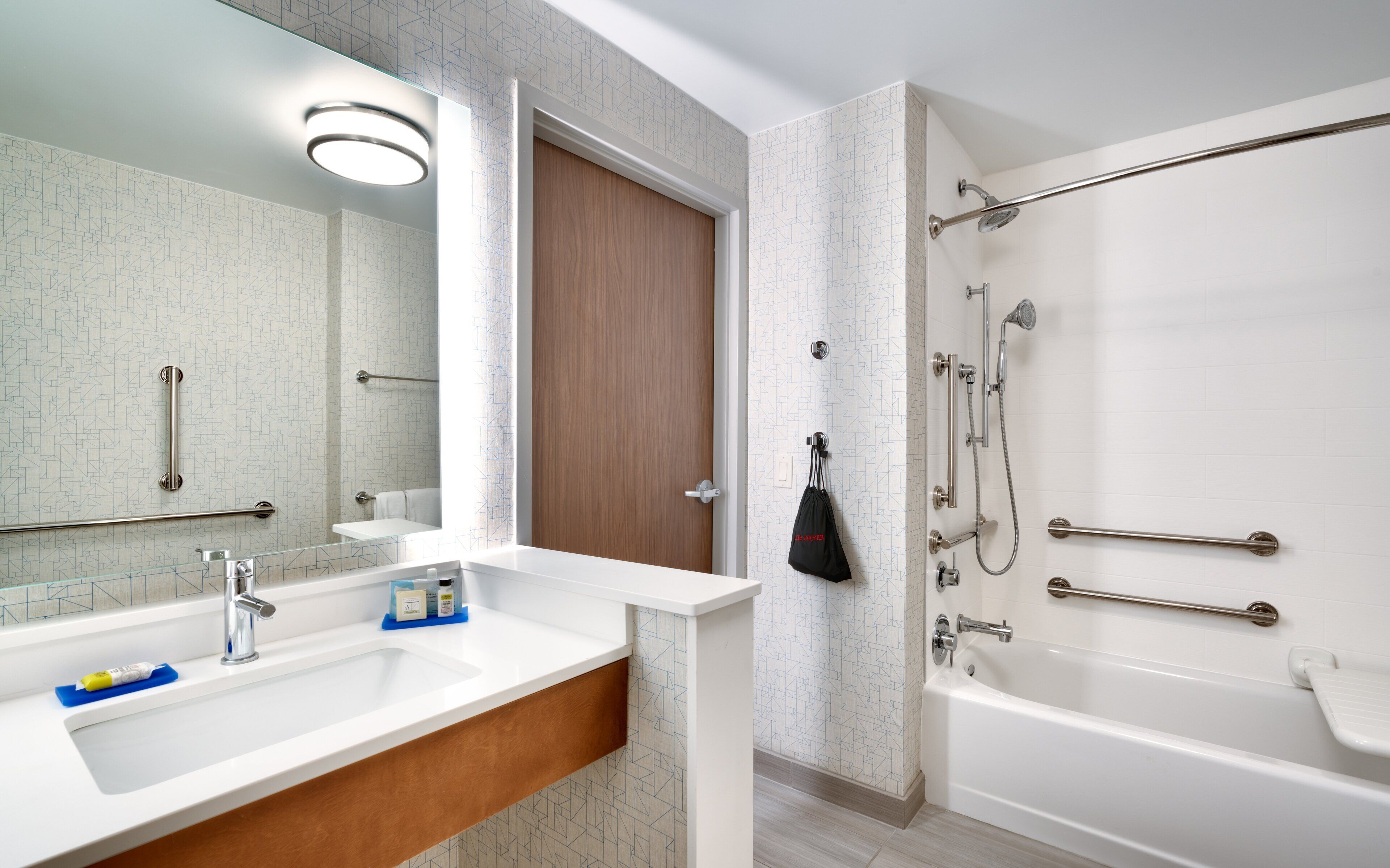 Un baño moderno con lavamanos, espejo y ducha blancos.