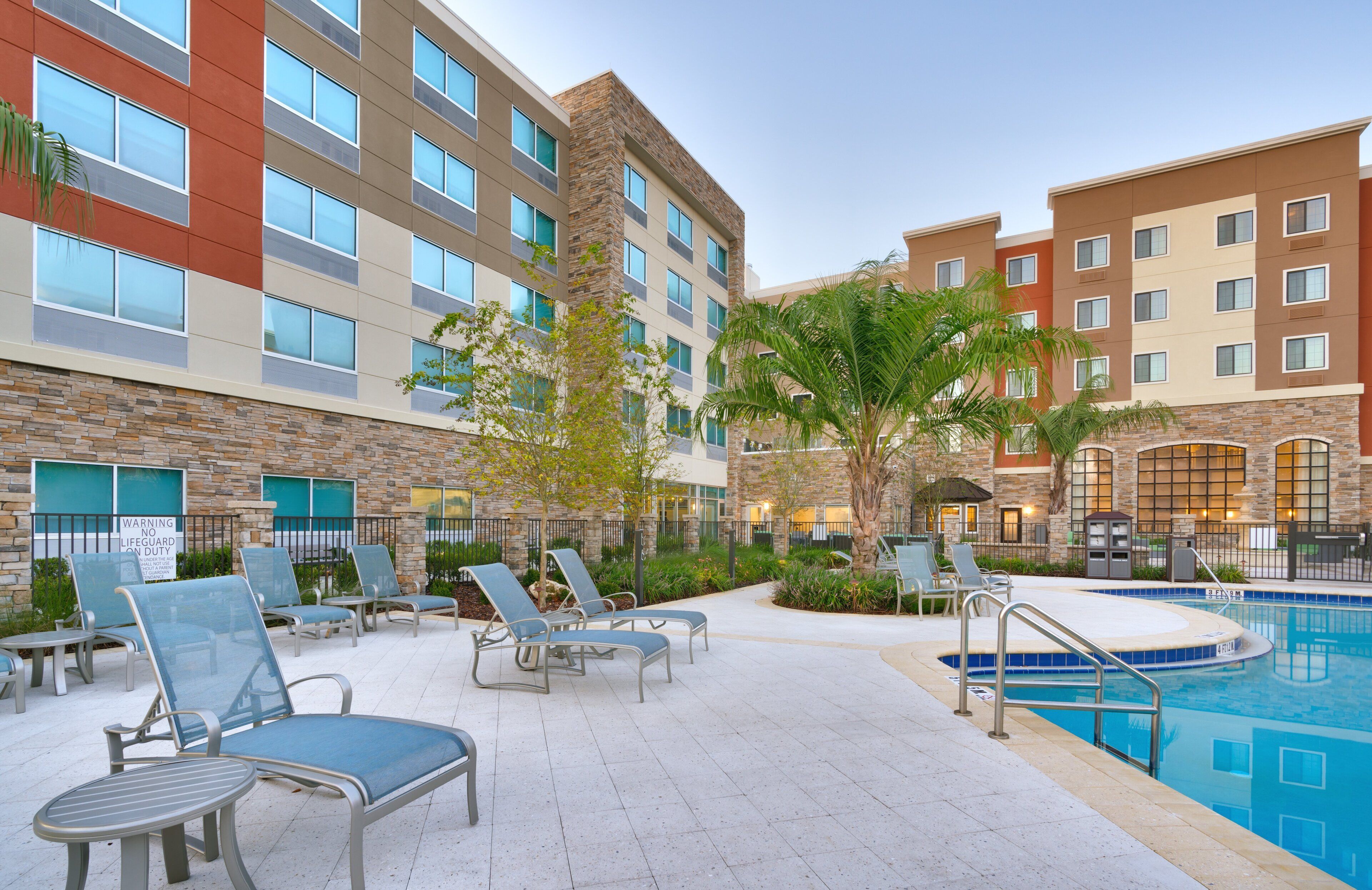 A hotel pool area with lounge chairs, a swimming pool, and a stone building facade.