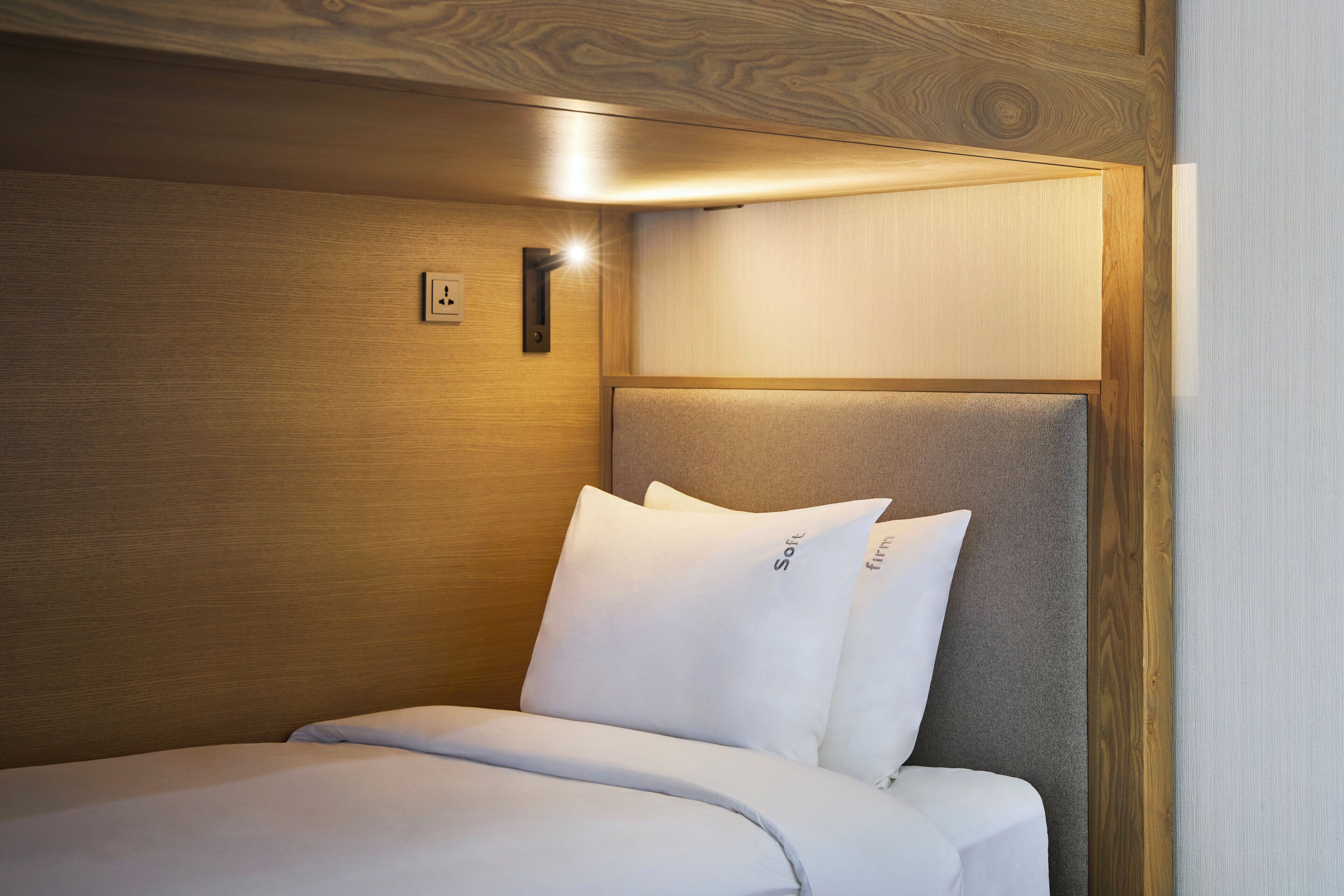 Una habitación de hotel con cabecera de madera, una lámpara de noche y una cama con ropa blanca.