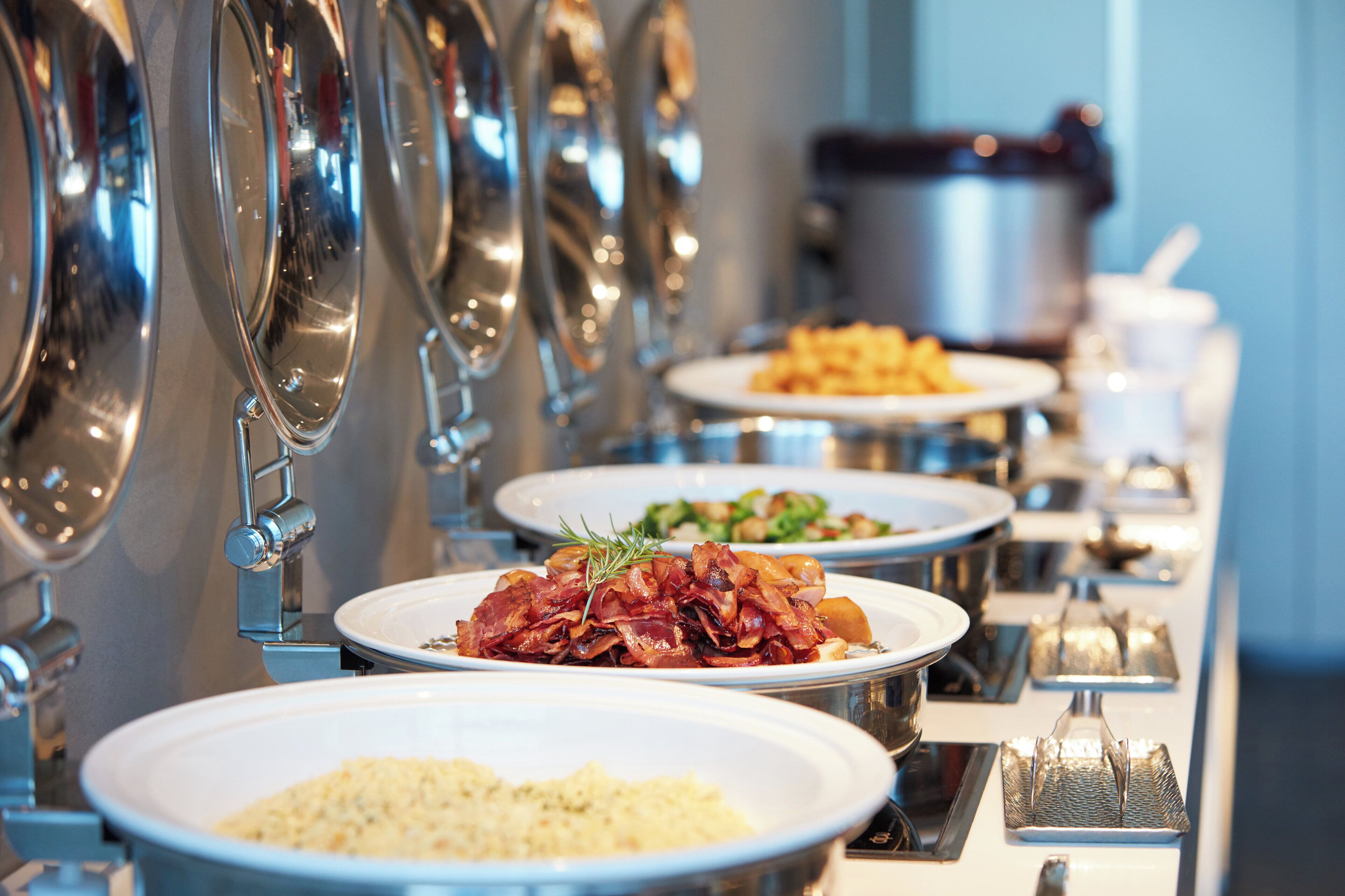 A buffet line with various dishes and a coffee station.