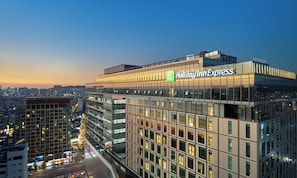 A Holiday Inn Express hotel with a modern glass facade, located in a cityscape at dusk. - Holiday Inn Express Seoul Hongdae by IHG (Seoul)