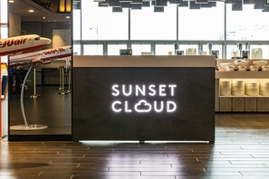 Een receptiebalie met een neonbord waarop 'Sunset Cloud' staat en een modelvliegtuig.