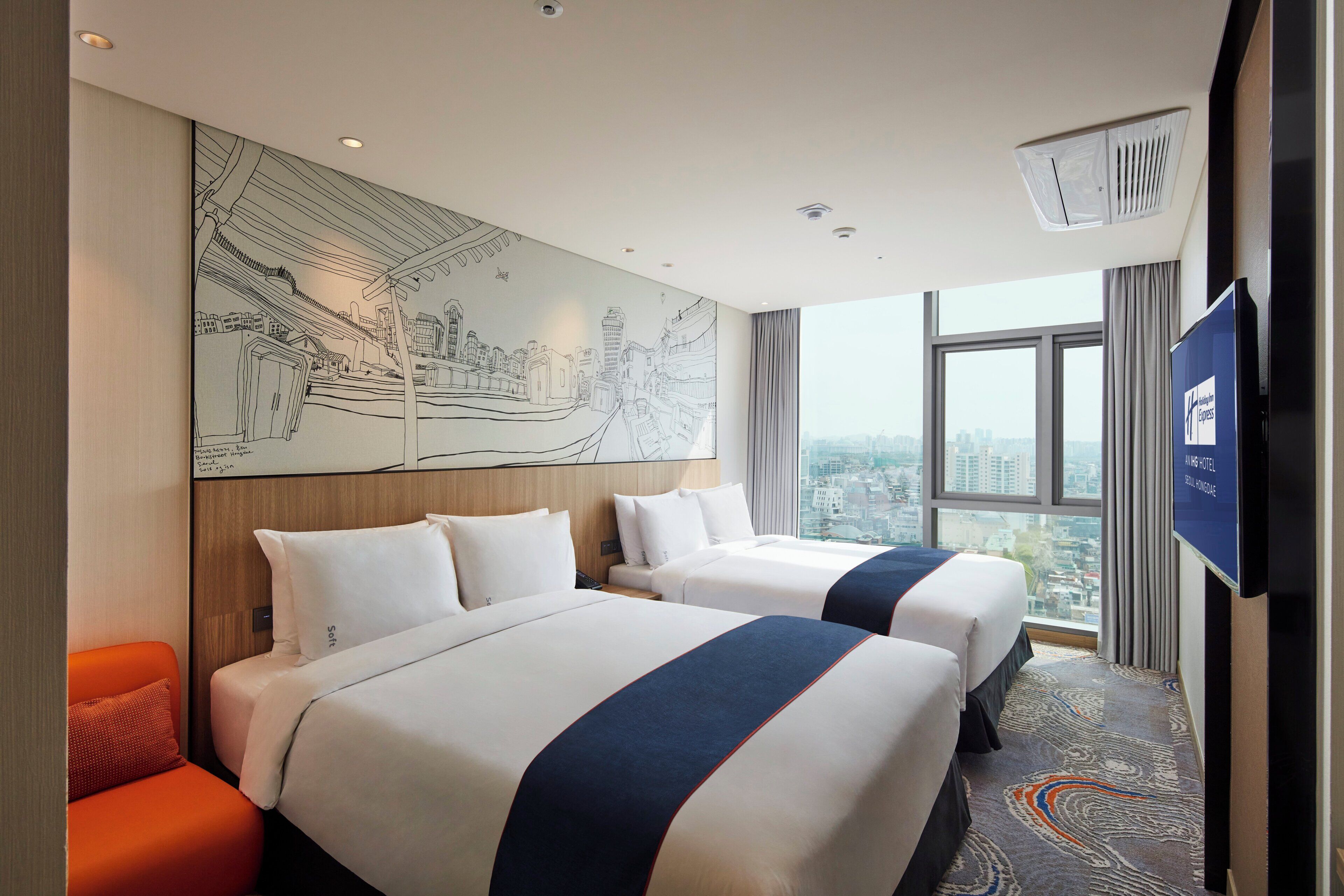 A hotel room with two beds, a cityscape view, a large wall mural, and a television.
