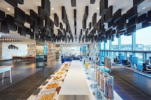 A modern cafe with a long counter displaying pastries and coffee machines. - Holiday Inn Express Seoul Hongdae by IHG (Seoul)