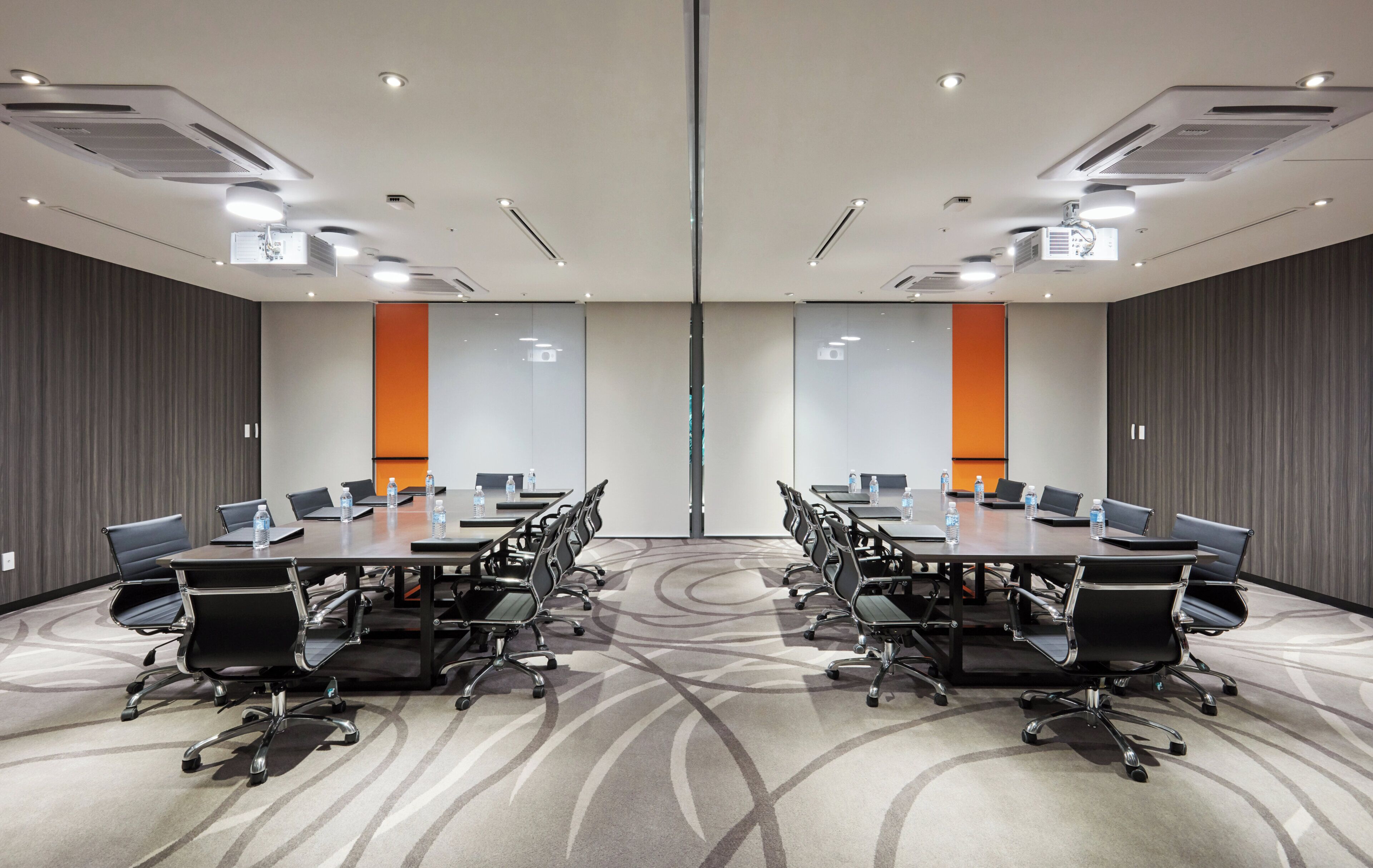 Uma sala de conferências com uma mesa grande, várias cadeiras e piso coberto de carpete.