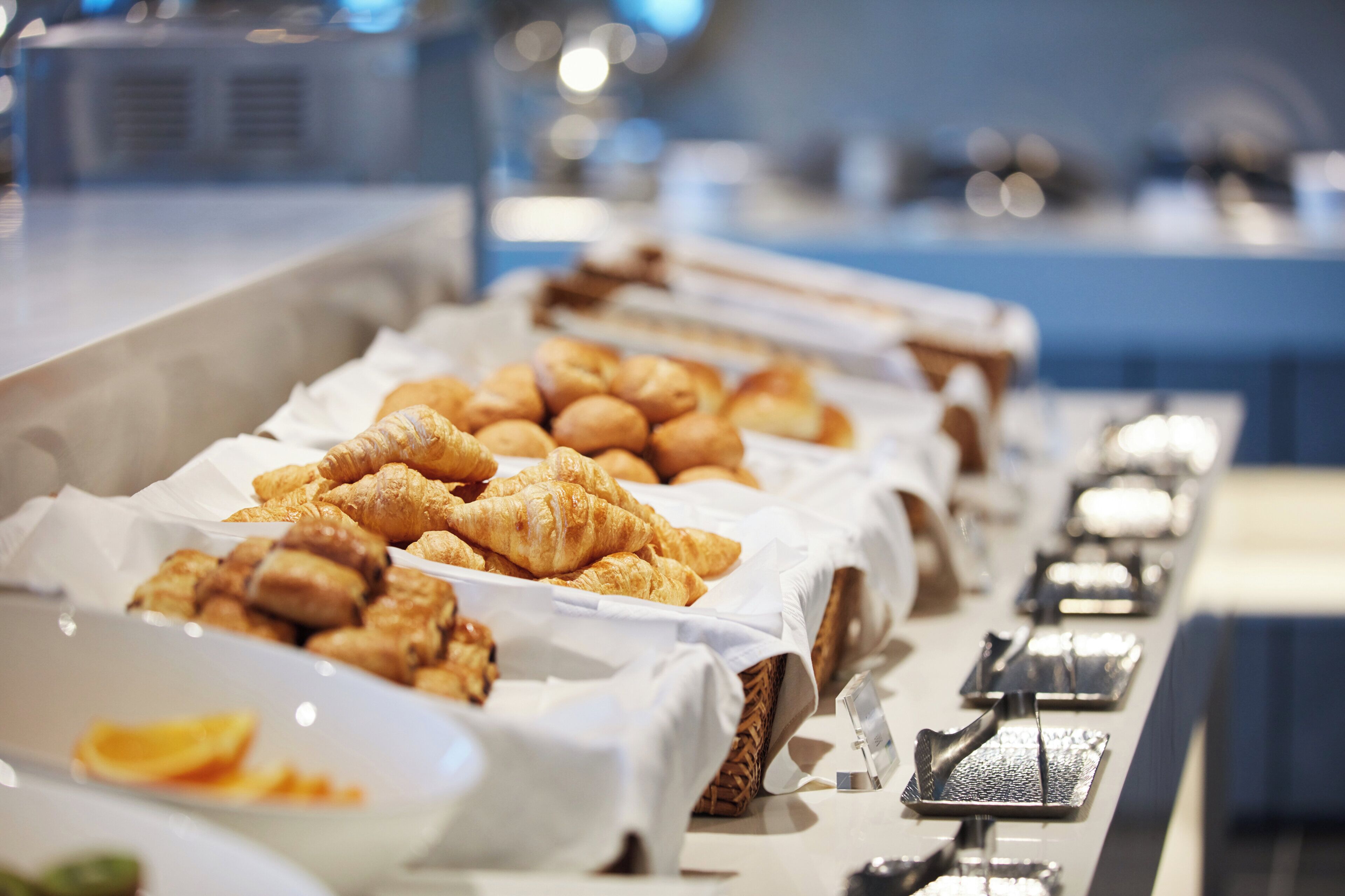 Un bufé con diversas opciones de panadería, incluyendo cruasanes y pasteles.