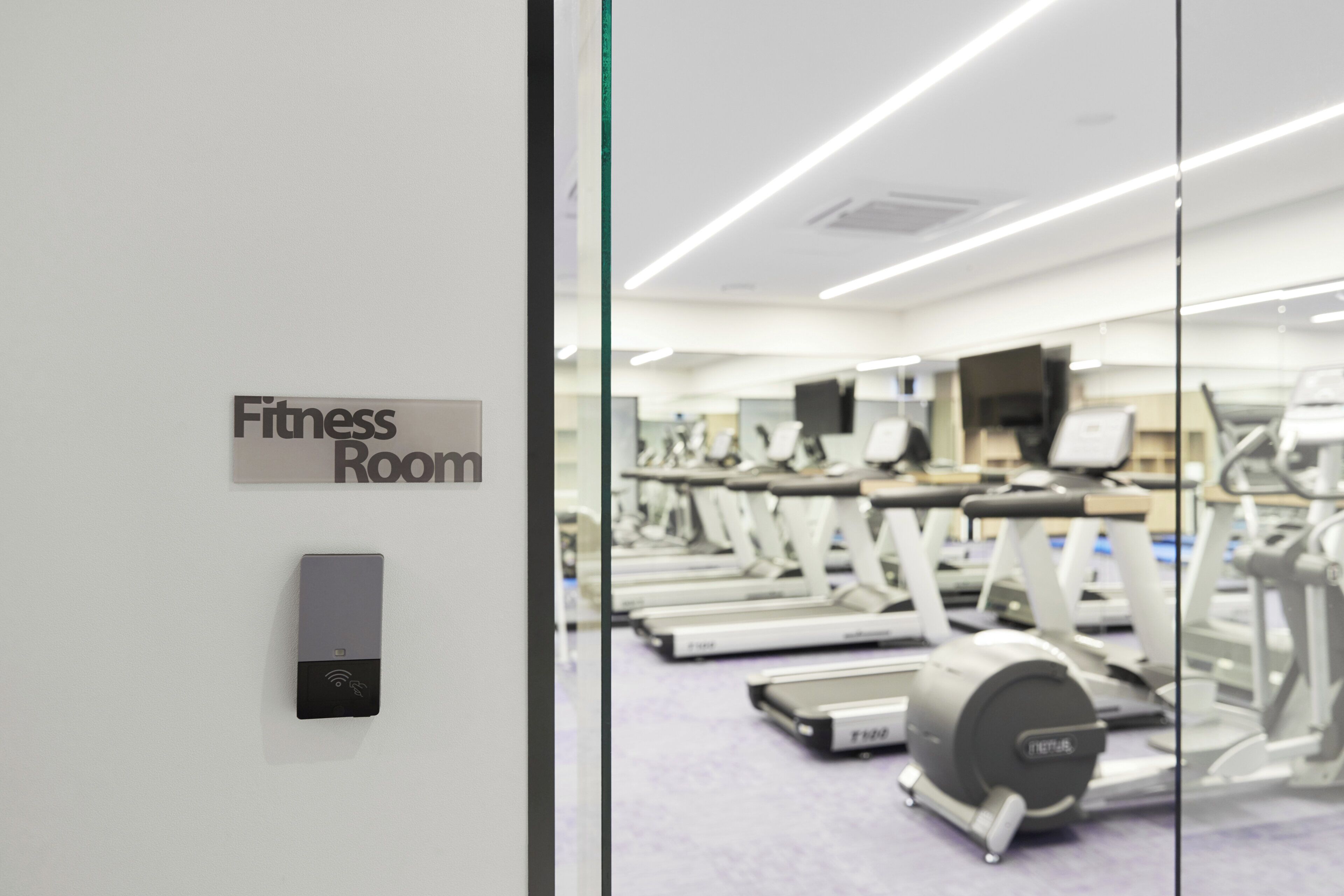 Ein Fitnessraum mit Schilder, Trainingsgeräten und einer Steuerung.