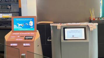 A self-check-in kiosk and a boarding pass machine at an airport.