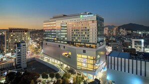 A multi-story hotel with a Holiday Inn Express sign, surrounded by other buildings and a cityscape at dusk.