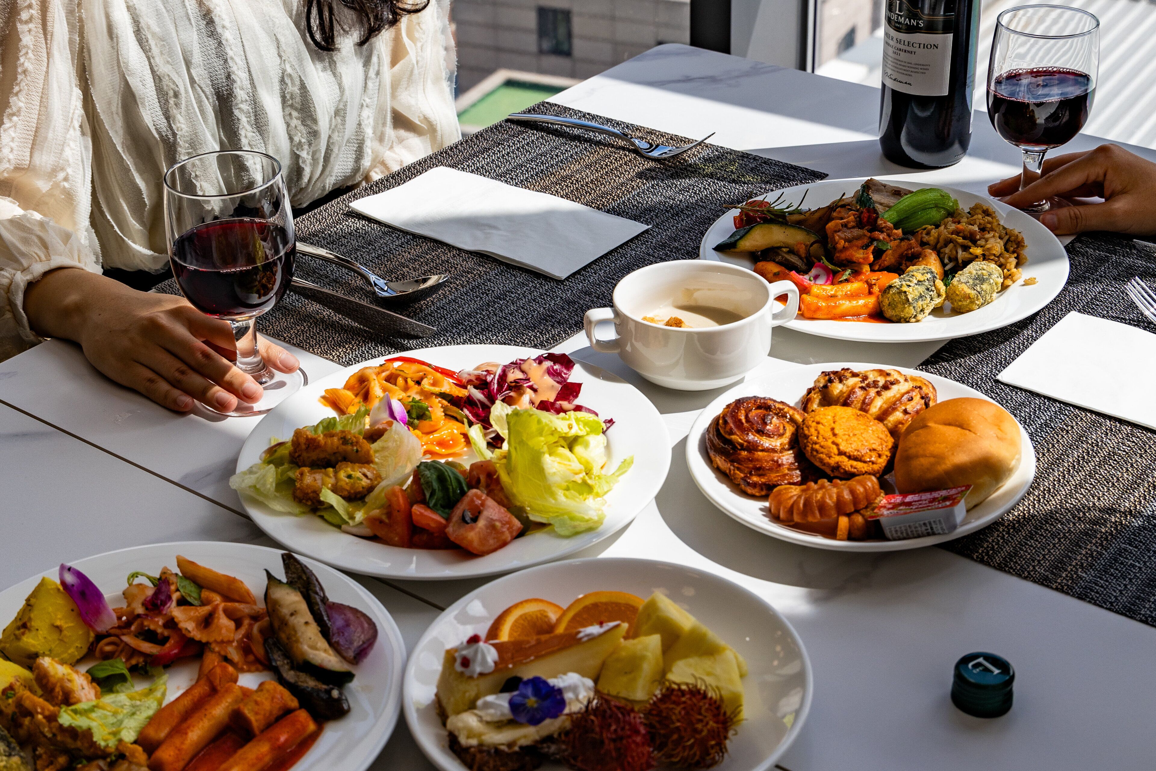 Una mesa servida con varios platos, copas de vino y una botella.