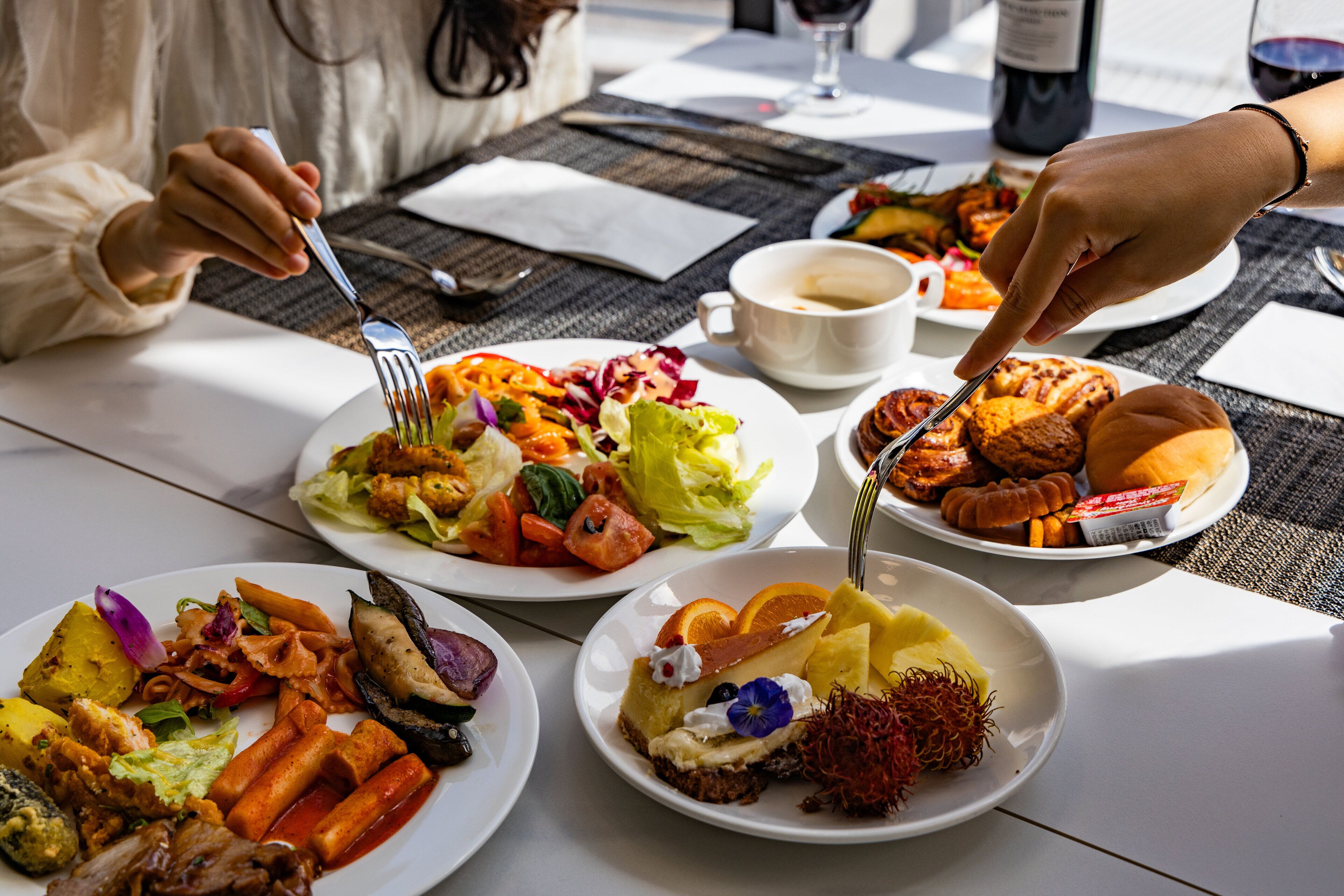 A table with various dishes, including salads, meats, and desserts, suggesting a dining setting.