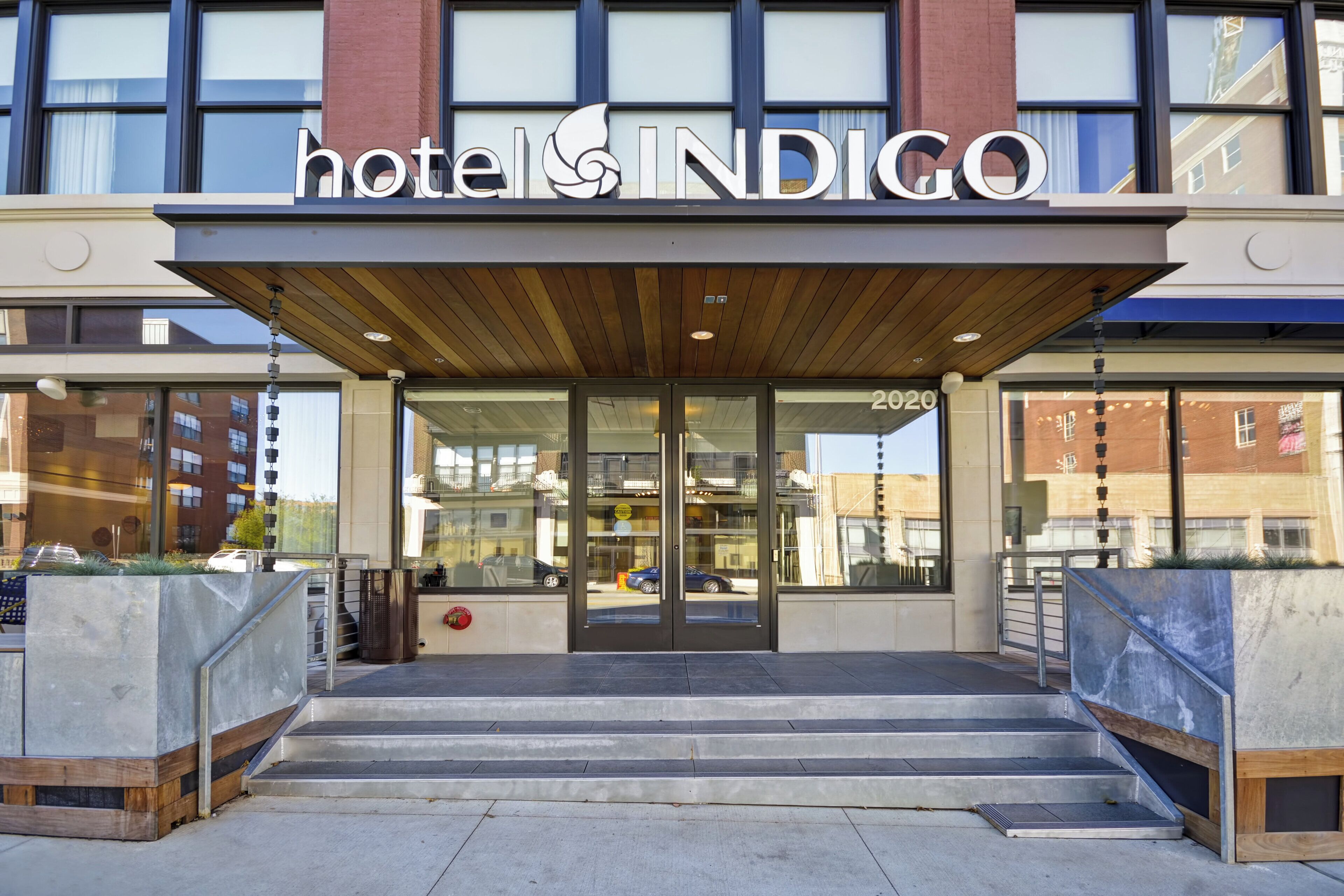 L'ingresso di un hotel dal design moderno, caratterizzato da un portico in legno e vetrate.