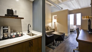 A modern kitchen with a coffee machine, sink, and wooden cabinets. The living area features a sofa, a small table, and a lamp. - Hotel Indigo Kansas City - The Crossroads by IHG (Kansas City)