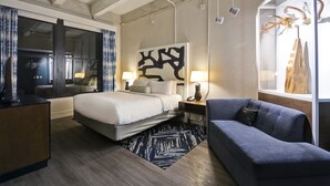 A modern hotel room with a large bed, a sofa, a desk, and a large window. - Hotel Indigo Kansas City - The Crossroads by IHG (Kansas City)