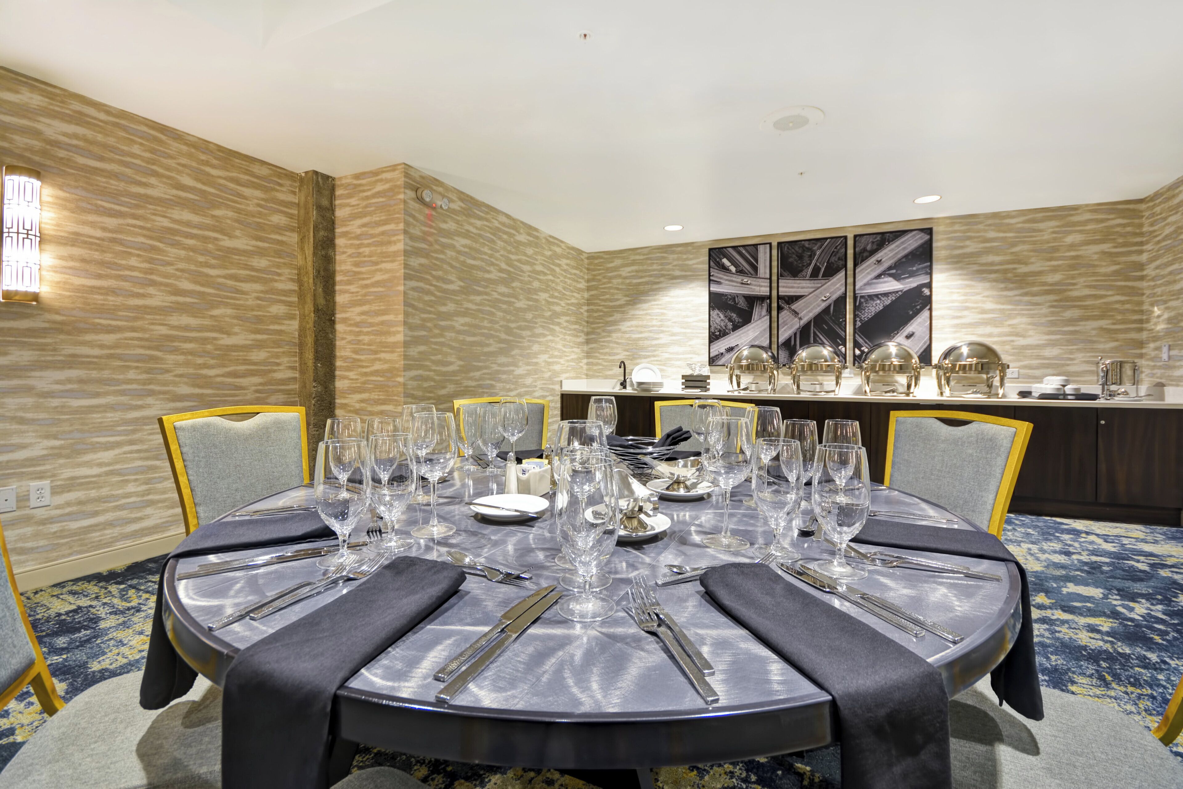 A dining area with a round table set for a meal, surrounded by chairs.