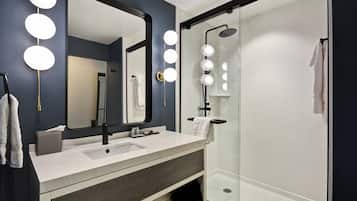 A modern bathroom with a large mirror, vanity, and a glass-enclosed shower.