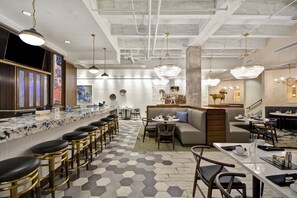 Un hall d’hôtel moderne doté d’un bar, d’espaces aménagés pour s’asseoir et d’éléments décoratifs.