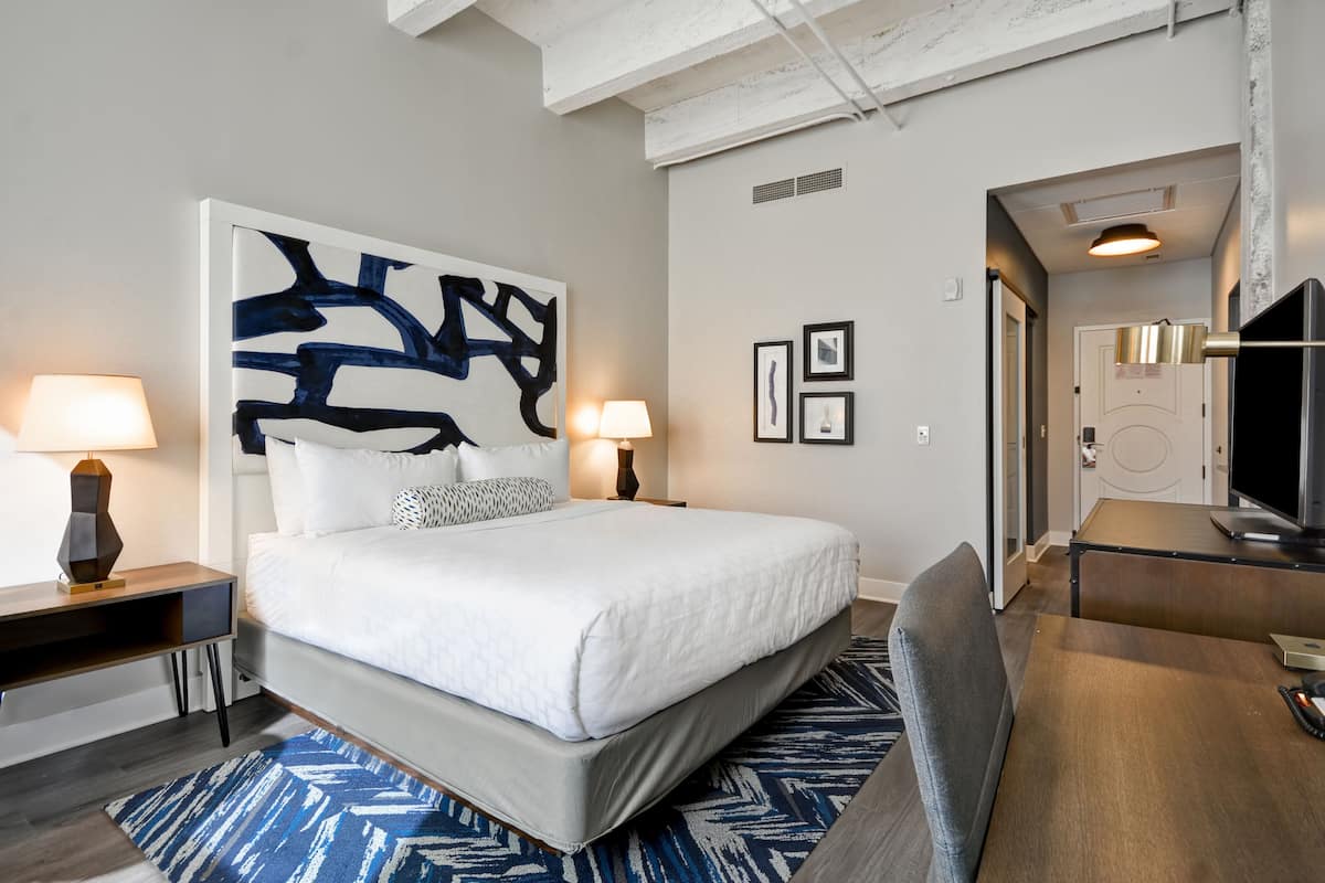 Une chambre d’hôtel moderne, dotée d’un grand lit, de lampes de chevet, d’un bureau et d’une télévision.