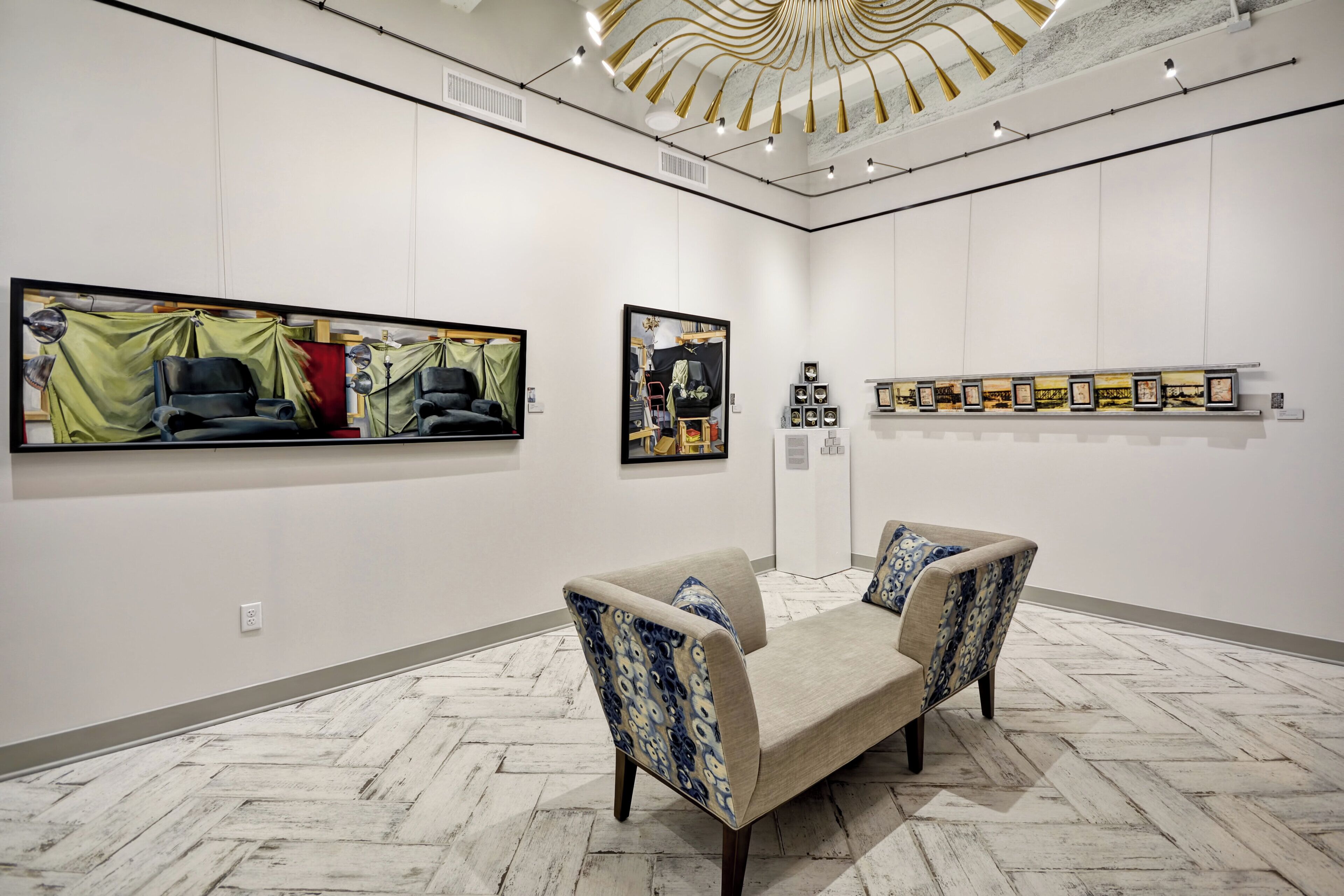 An art gallery with paintings on the walls, a sofa, and a patterned floor.