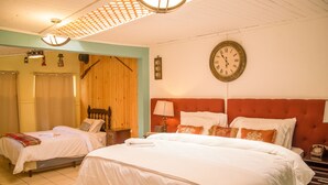 A hotel room with two beds, a wooden wardrobe, a clock on the wall, and a ceiling fan. - Hotel Vintage Casa las Flores (Quetzaltenango)