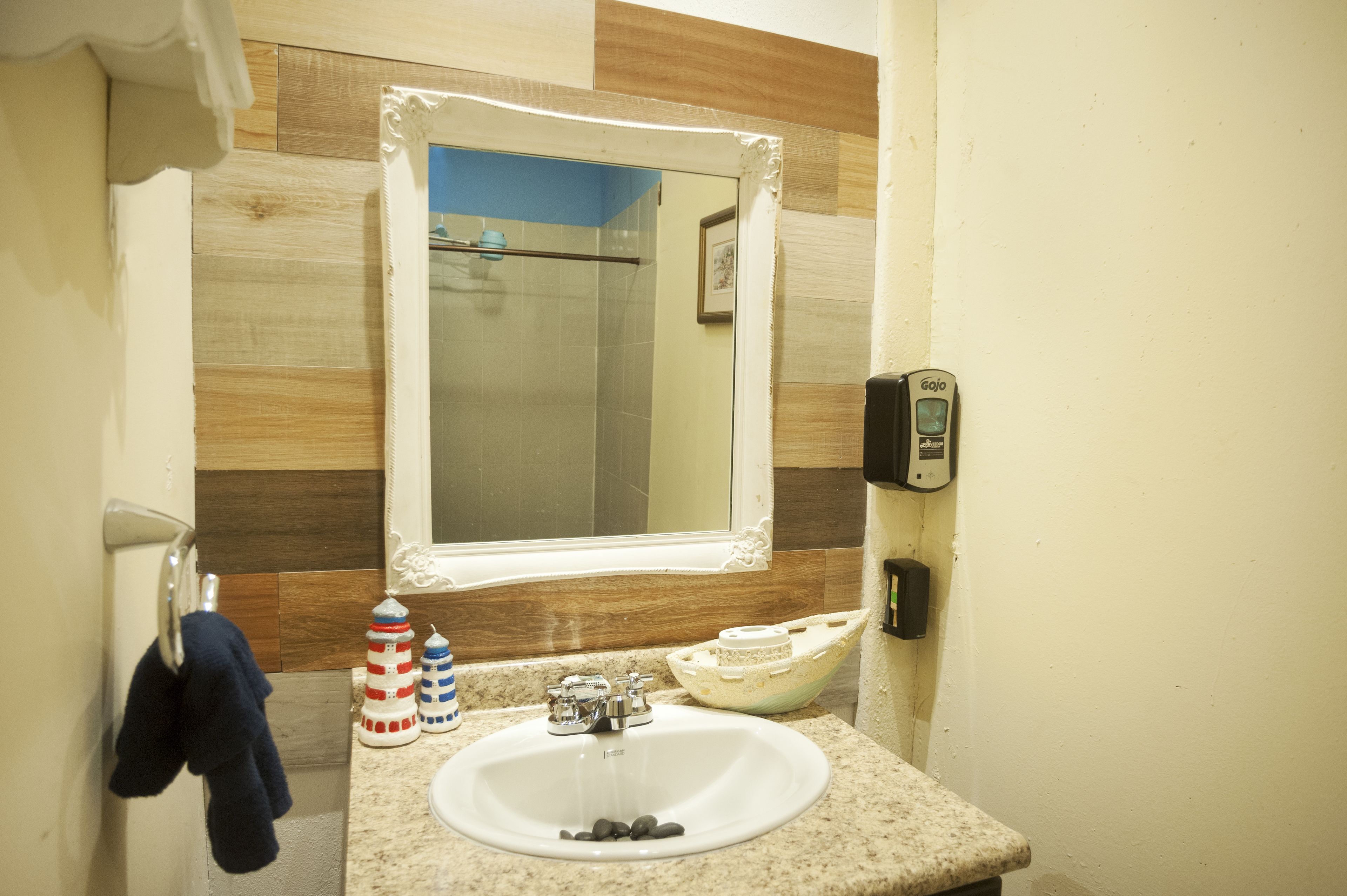 A bathroom with a white sink, a mirror, and a soap dispenser.