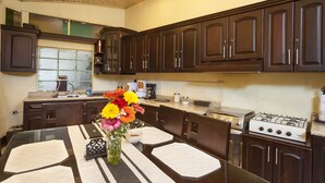A kitchen with dark wooden cabinets, a gas stove, a microwave, and a dining table with placemats. - Hotel Vintage Casa las Flores (Quetzaltenango)