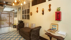 A cozy living room with a brown sofa, patterned cushions, a vintage record player, and a red telephone booth decoration. - Hotel Vintage Casa las Flores (Quetzaltenango)