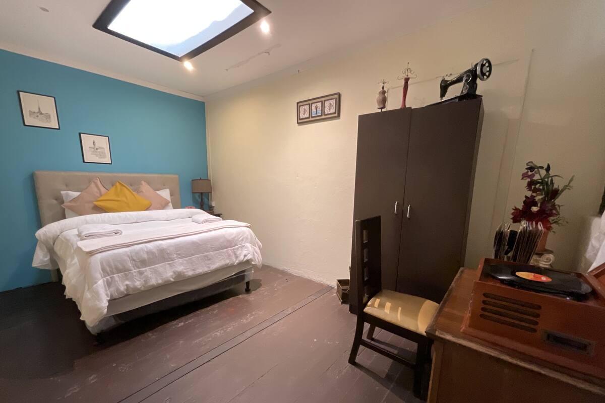 Un dormitorio con cama, armario, escritorio y tragaluz.