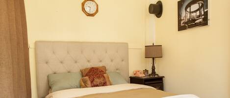 A bedroom with a bed, a clock, a nightstand, a lamp, and a bicycle light fixture.