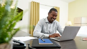A man working at a desk with a laptop, papers, and a phone. - Candlewood Suites Austin North by IHG (Austin)