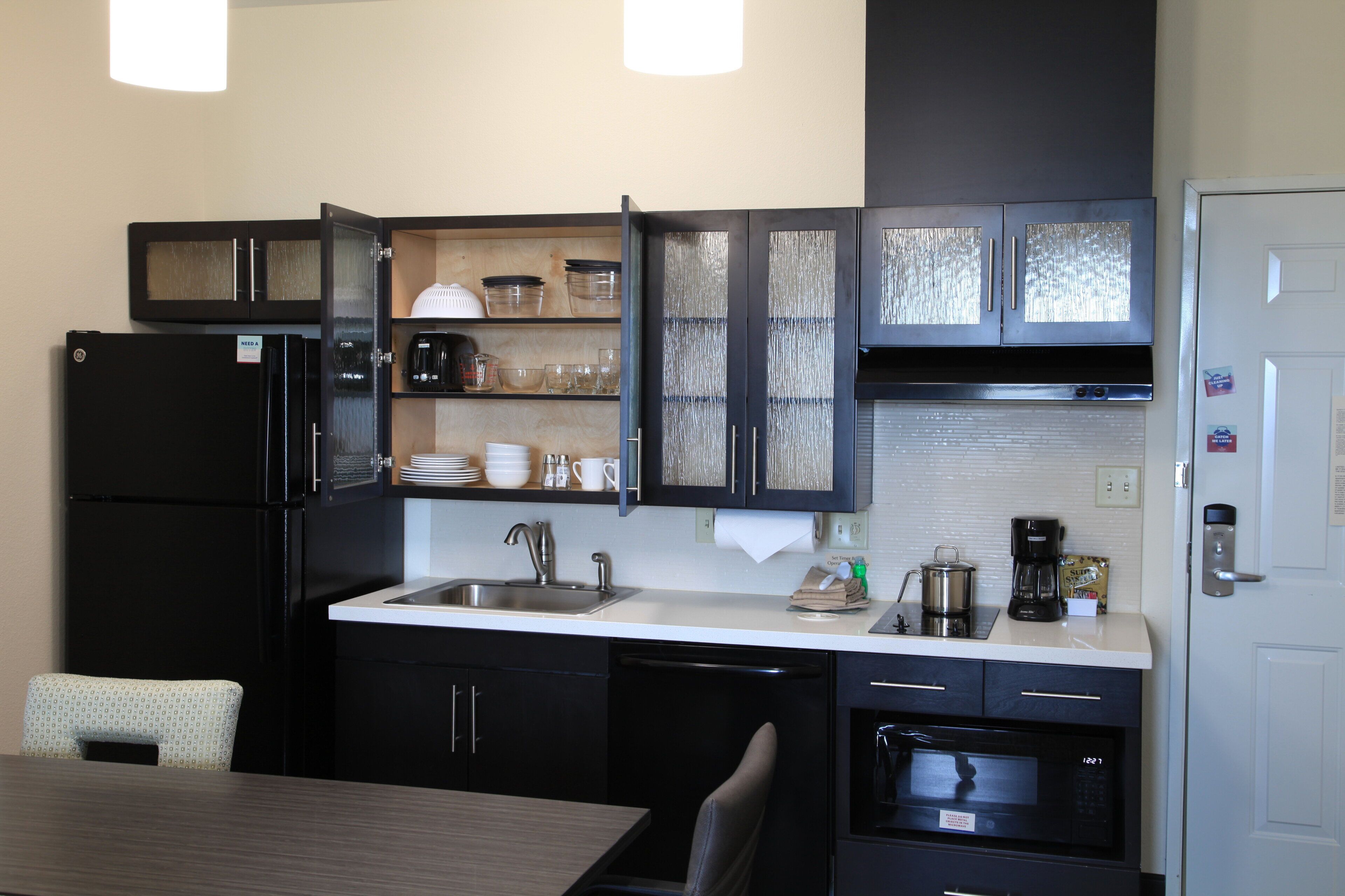 A compact kitchen with a refrigerator, sink, and microwave.