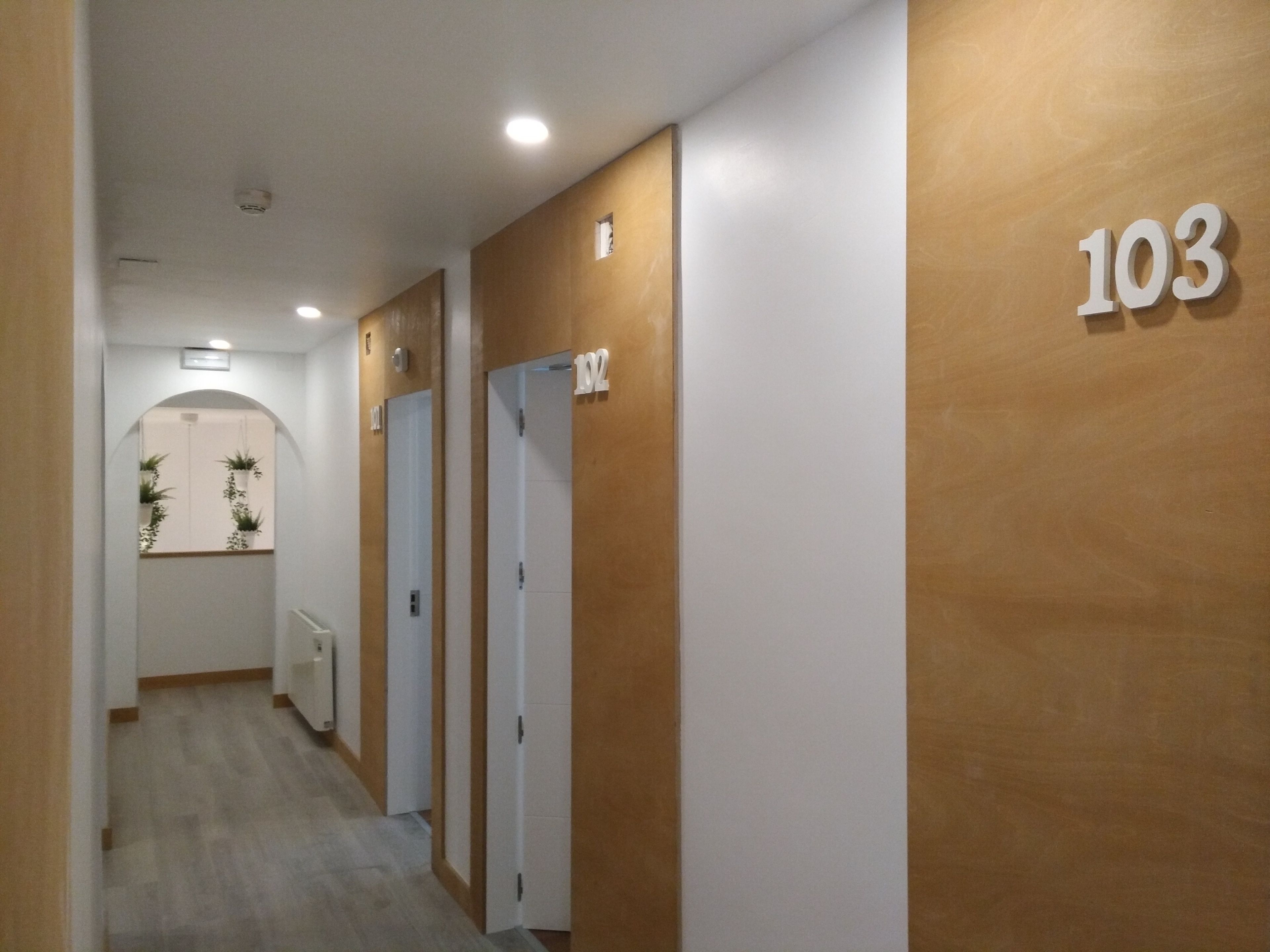 A hallway with doors numbered 101 to 103, wooden walls, and a radiator on the left.