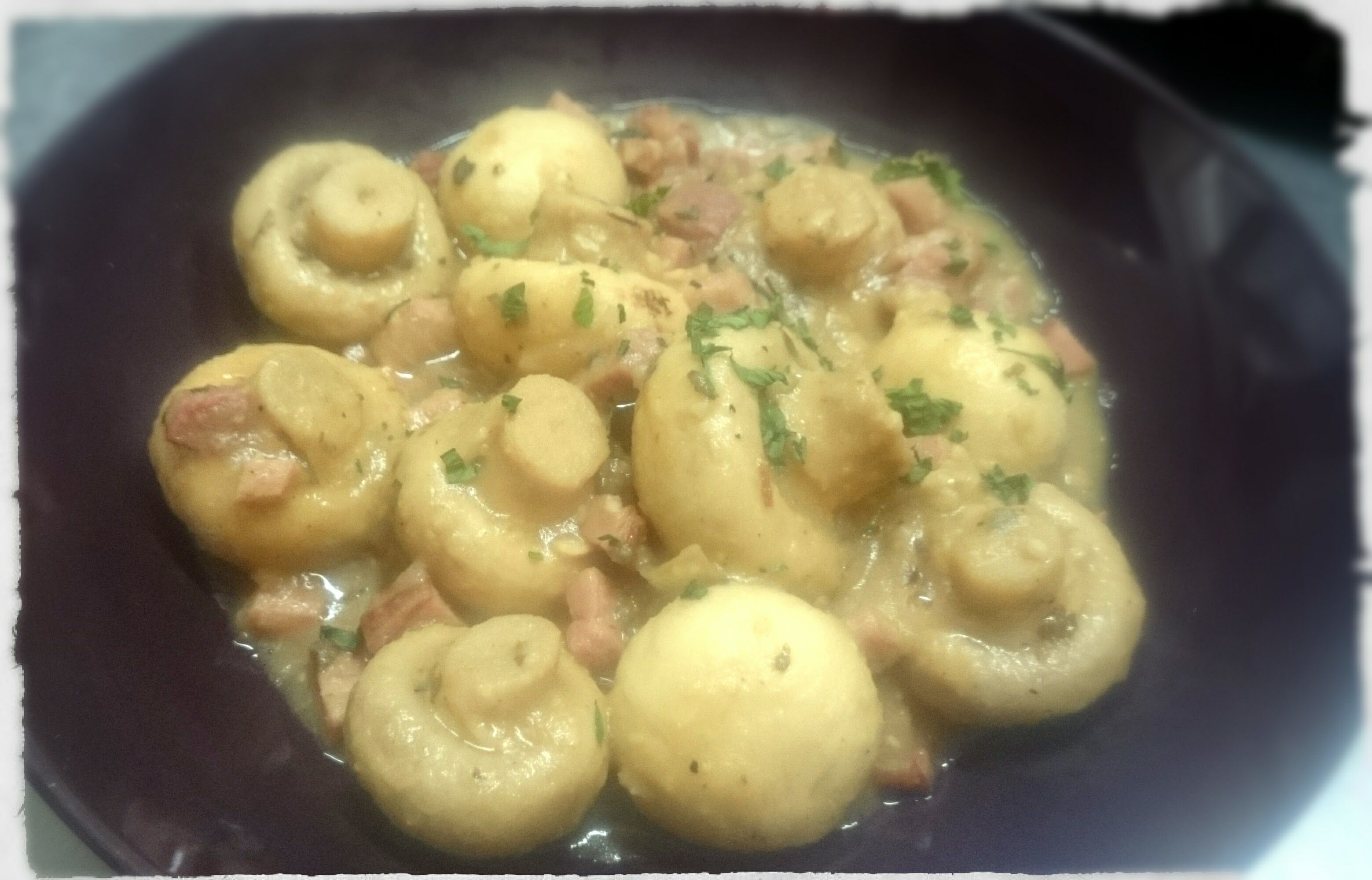 Un plato de patatas con jamón y hierbas aromáticas.