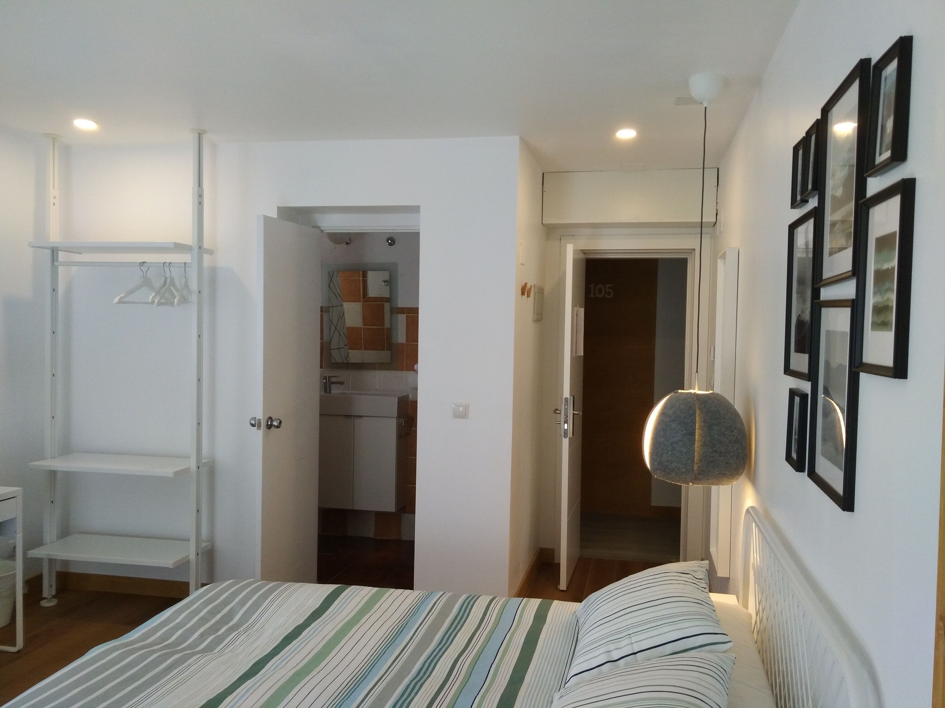 Een slaapkamer met een bed, een kledingkast, een spiegel en een deur naar een badkamer.