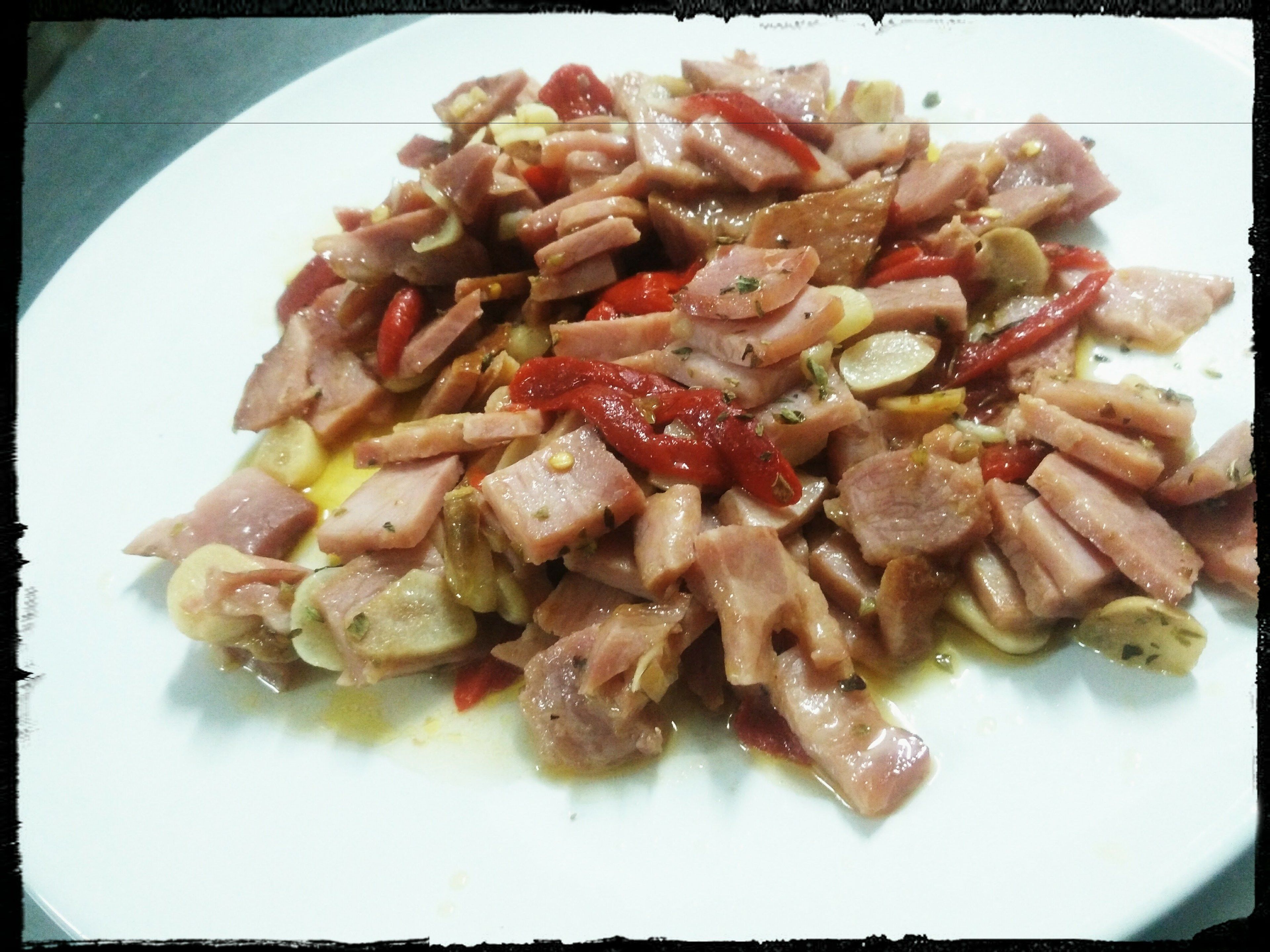 Un plato de carne en rodajas con verduras y un chorrito de aceite.